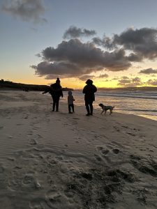 A family walk with a dog at sunset on Gwithian Townas beach
