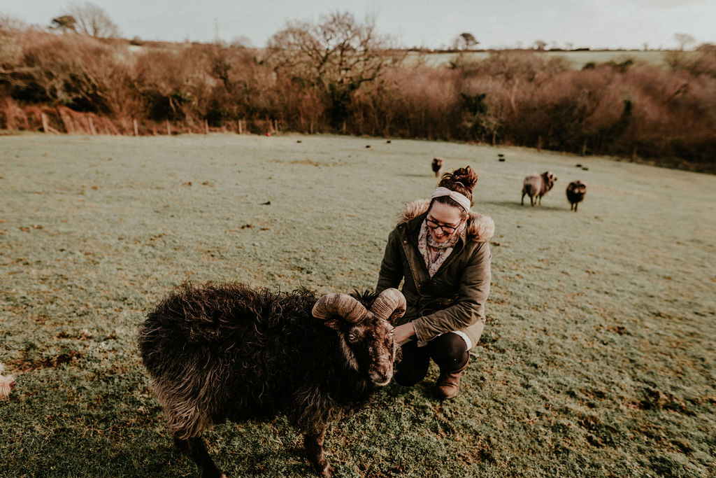 Maria is crouched down next to Alaistair one of their North Ronaldsay sheep at Higher Trewithen in Cornwall.